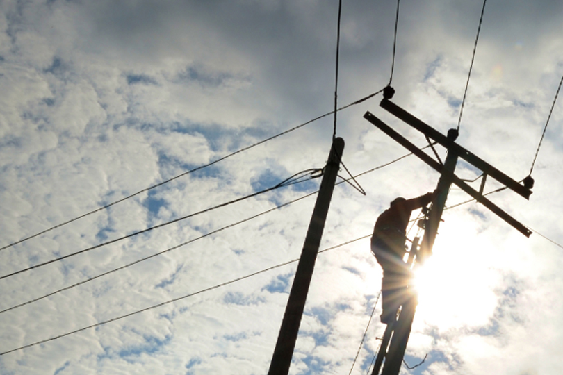 Line Worker on utility pole working on overhead power lines